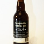 A dark brown beer bottle with a black label featuring white text in Latvian, reading “Pētermuižas tumšais alus Nr. 3.” The label includes additional small text and a barcode at the bottom. The bottle is set against a plain white background.