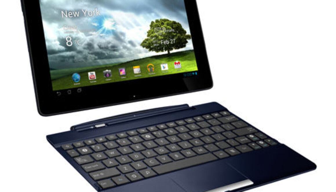 A black Asus tablet attached to a keyboard dock, resembling a small laptop. The tablet screen displays a weather app with "New York," cloudy skies, and 8°C. Date shown is February 27. Various app icons are visible below the weather display. The keyboard is dark and compact.