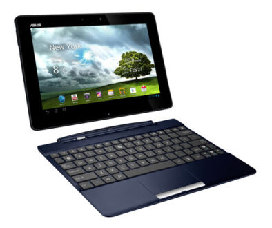 A black Asus tablet attached to a keyboard dock, resembling a small laptop. The tablet screen displays a weather app with "New York," cloudy skies, and 8°C. Date shown is February 27. Various app icons are visible below the weather display. The keyboard is dark and compact.